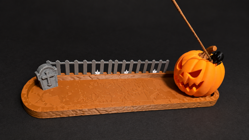 3D printed orange Halloween pumpkin incense holder with tombstone and fence